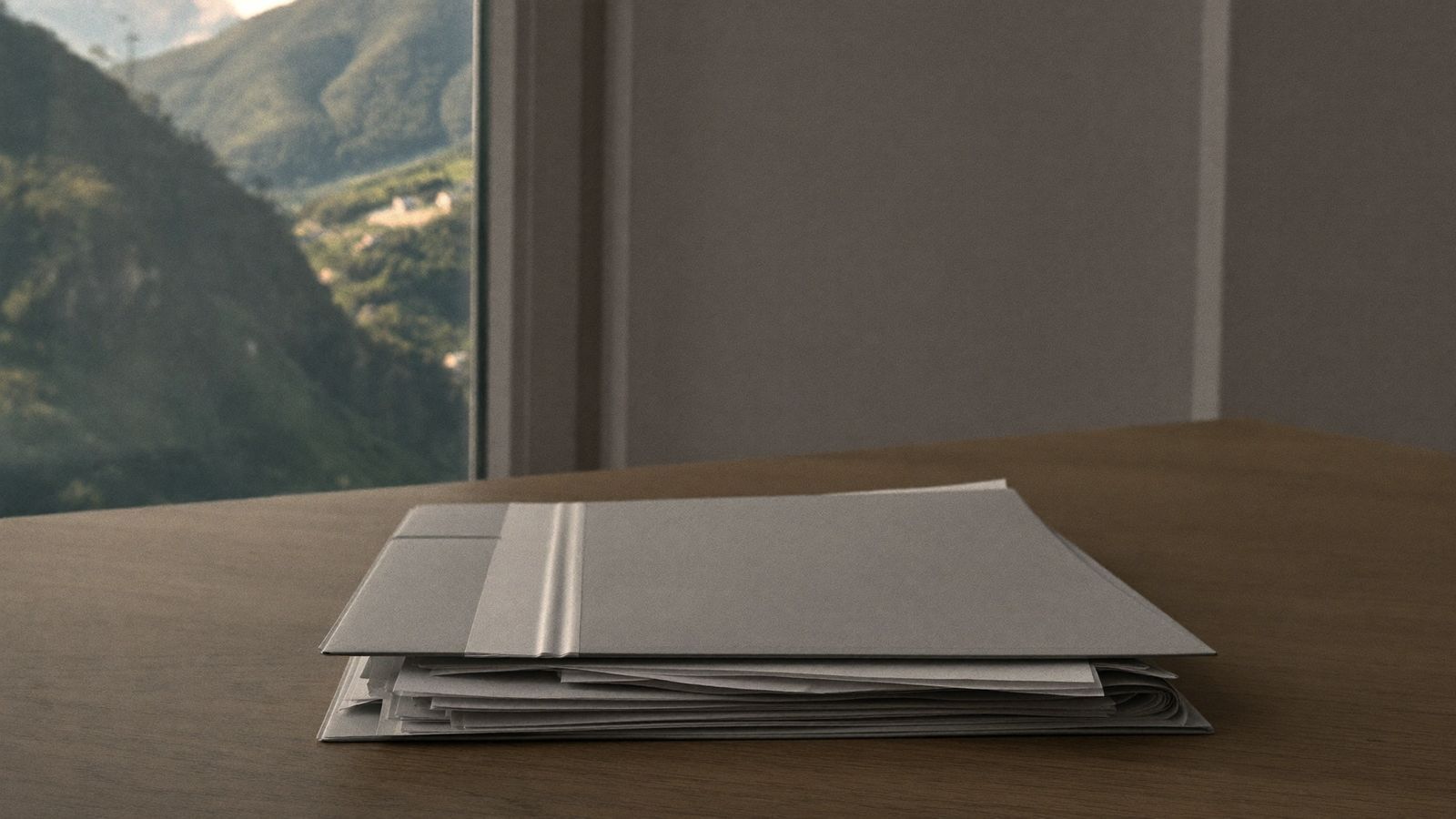 Ein Aktenordner mit Unterlagen auf einem Holztisch, im Hintergrund ein Fenster mit Bergblick